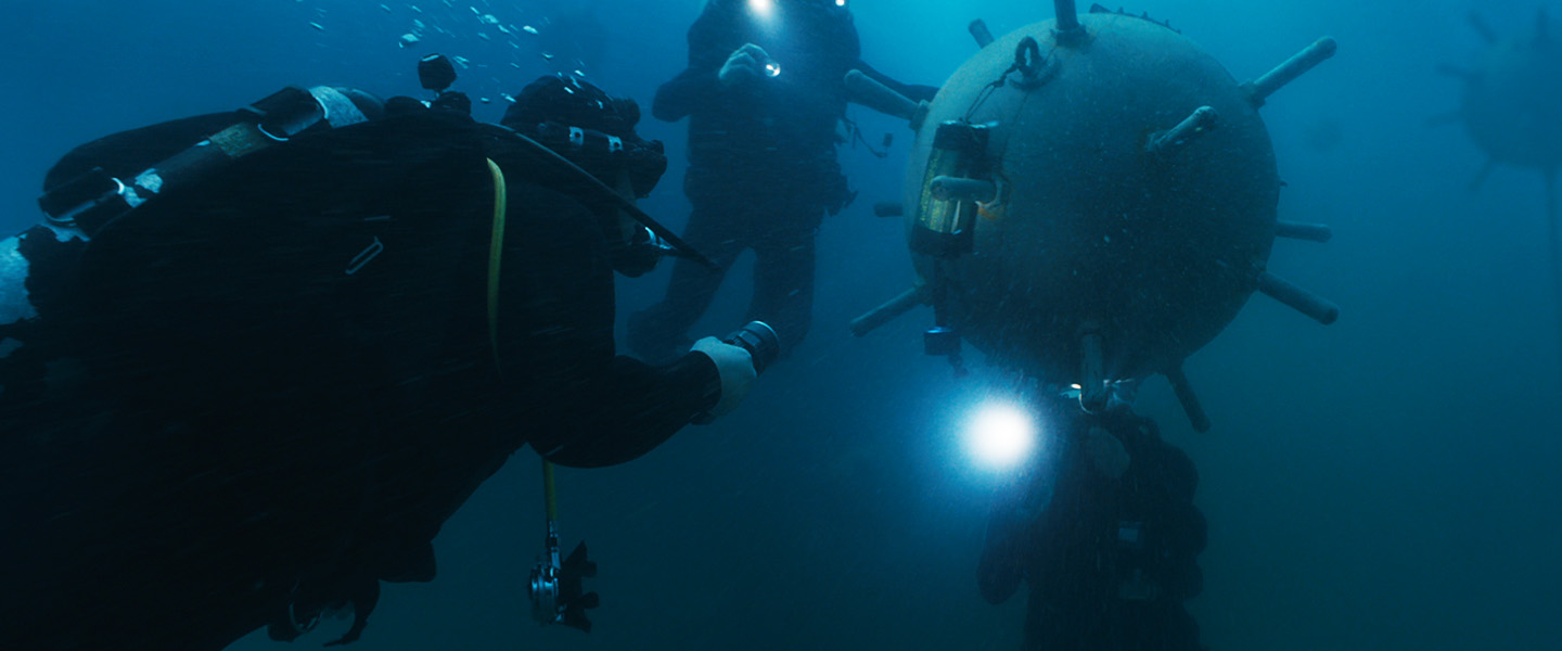 Explosive Ordnance Disposal Technicians inspect an underwater mine using specialized diving gear and expertise to ensure safety and mission success.