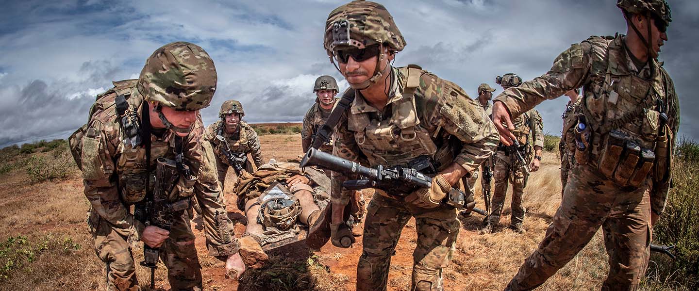 Special Amphibious Reconnaissance Corpsmen conduct Tactical Combat Casualty Care training, assisting soldiers in a simulated battlefield medical scenario.