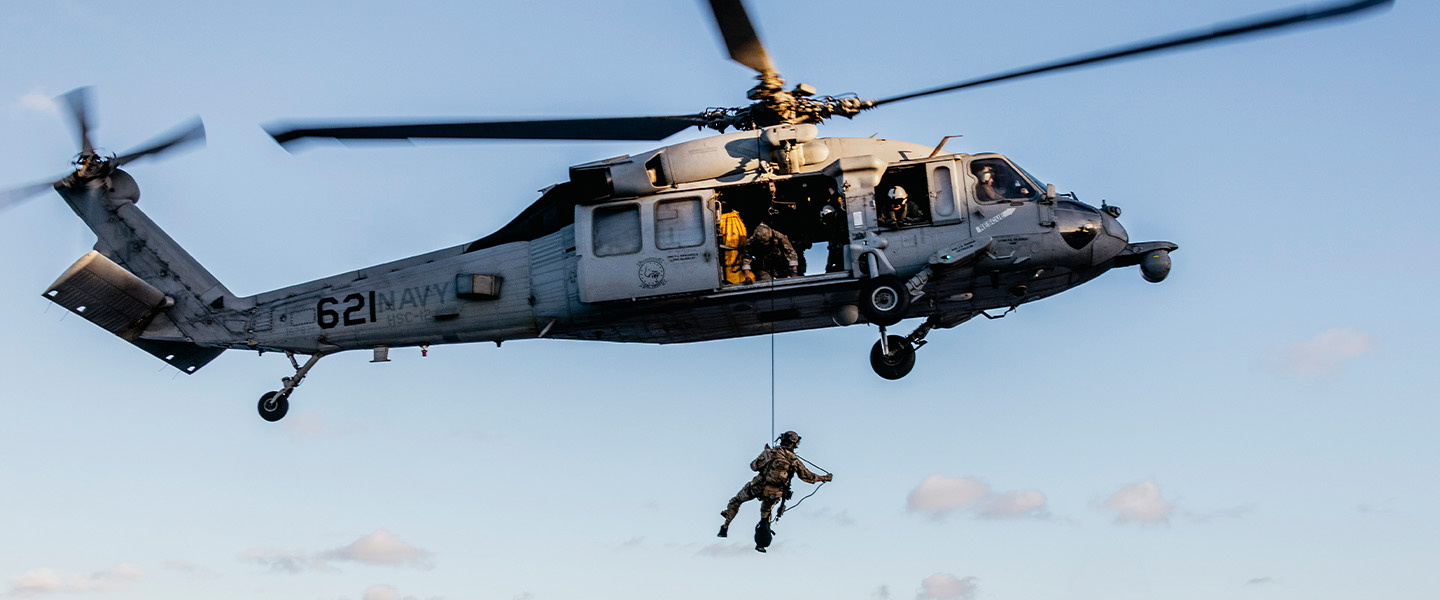 Explosive Ordnance Disposal Technicians fast-rope from an MH-60S Seahawk Helicopter onto the flight deck of USS George Washington.