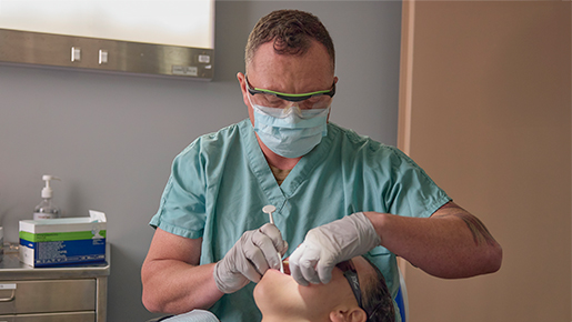 Navy dentist performing a dental procedure on a patient in a clinic setting.
