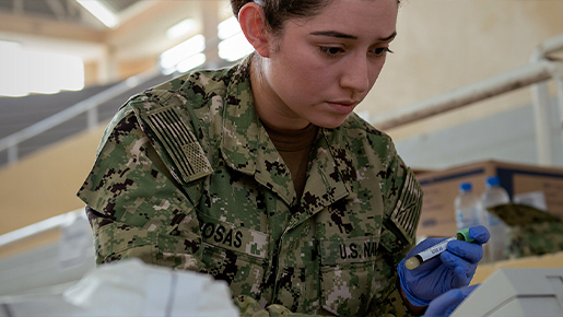 Navy medical technician analyzing a lab sample using scientific equipment for diagnostic testing.