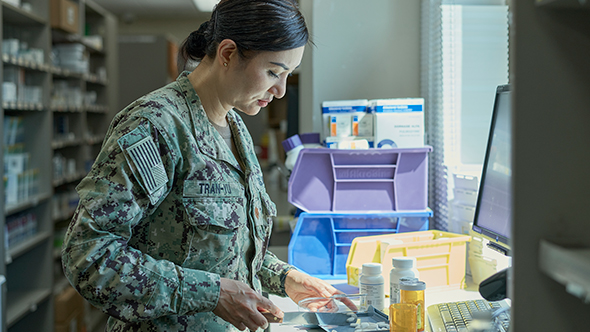 Navy pharmacist carefully counting pills in a pharmacy, ensuring accurate medication dispensing.