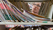 Navy medical records worker searching through overflowing file shelves for patient information.