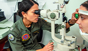 Navy optometrist using specialized equipment to examine a patient's eyes during an eye exam.