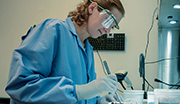 Navy medical research technician in protective gear working with samples in a laboratory setting.