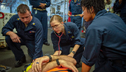 Navy medical team assisting a patient on a stretcher, providing emergency medical care and support.