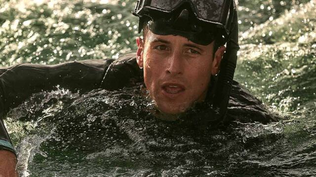 A Navy Aviation Rescue Swimmer navigates through turbulent ocean waves, showcasing skill and resilience during a challenging rescue training exercise.