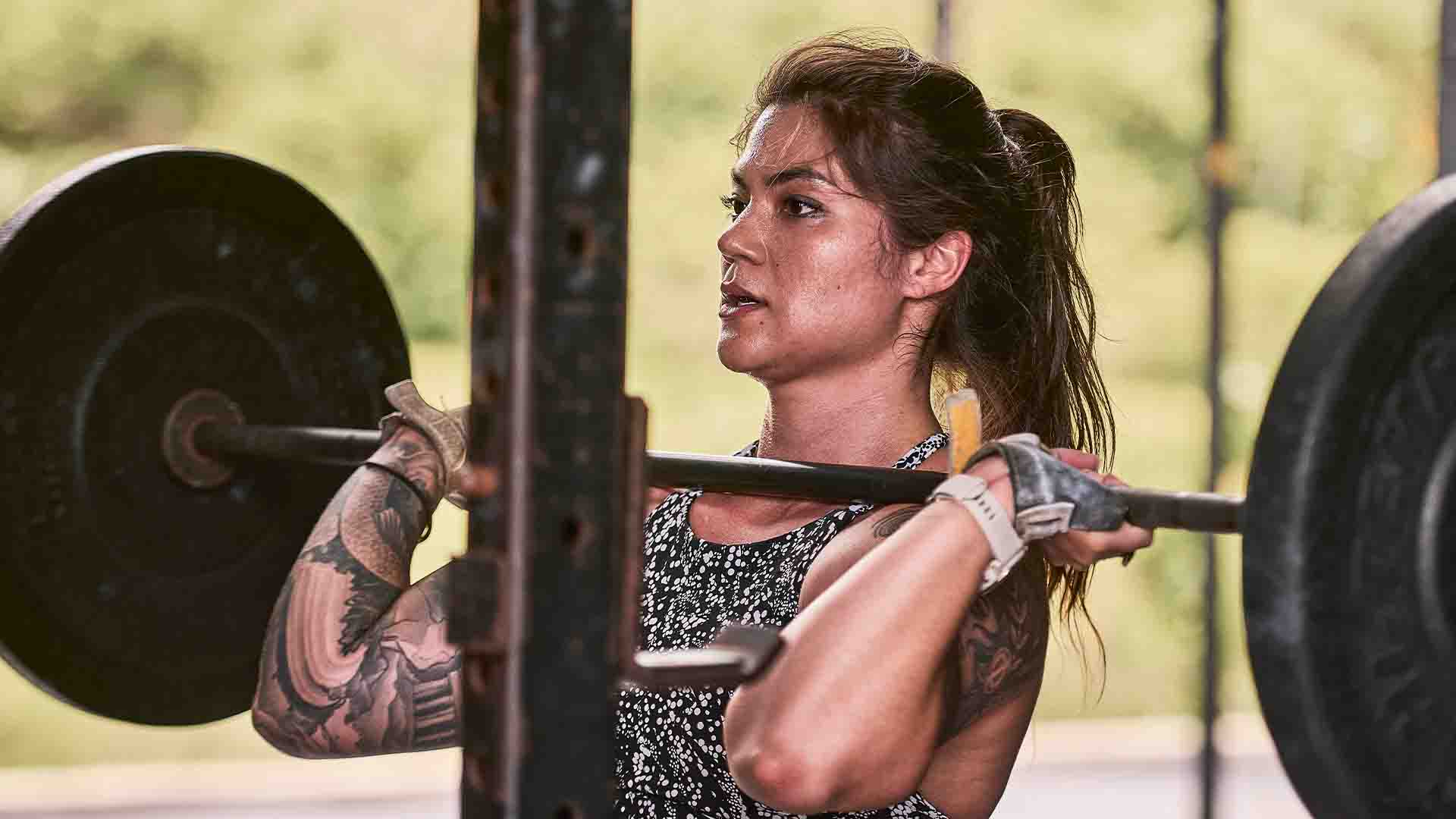 Navy Lieutenant Commander Mia Edgar lifts a barbell in a gym.