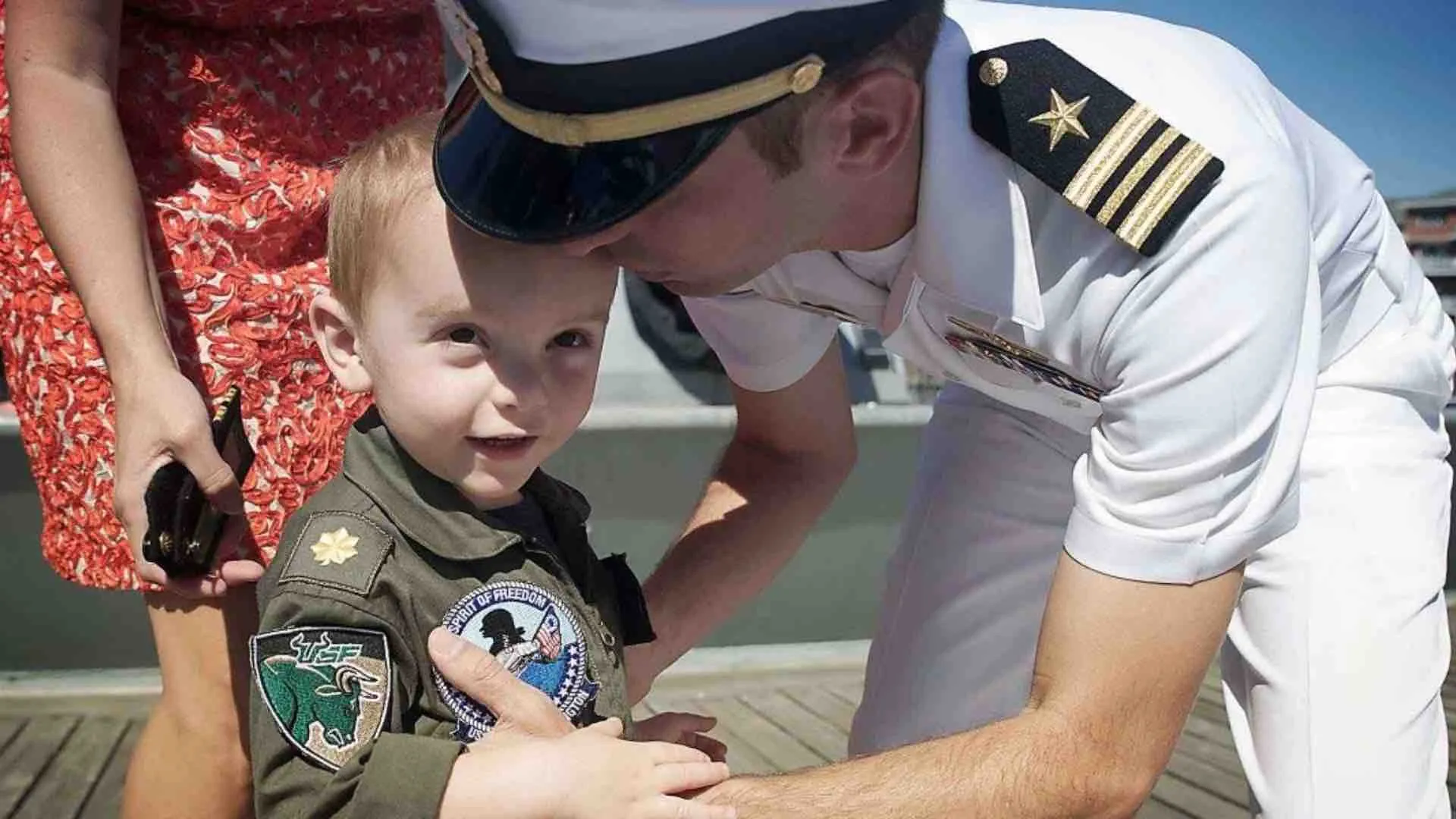 Navy Lieutenant Commander in uniform greets a young child